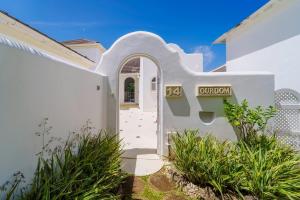 ein weißes Haus mit einem Torbogen davor in der Unterkunft Royal Westmoreland - Cassia Heights 14 townhouse in Saint James