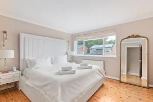 a white bedroom with a large white bed and a mirror at Guildford - 4 Bedroom House - Private Parking in Guildford