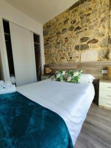 a bedroom with a large bed with a stone wall at Apartamentos Principe in Vigo
