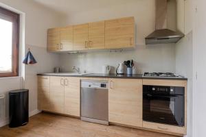 a kitchen with wooden cabinets and a stove top oven at Appartement au cœur de la Vallée de la Maurienne in Saint-Julien-Mont-denis