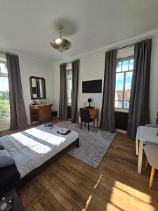 a bedroom with a bed and a desk and windows at La Villa Santina in Rethel