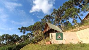 a building on a hill with trees in the background at Chalés Capivari Diamante in Campos do Jordão