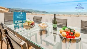Una mesa de cristal con dos cuencos de fruta y una botella de vino. en Casa Estrella Marina del Este, en La Herradura