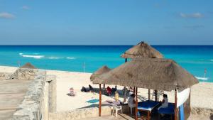 un grupo de personas sentadas en sillas bajo sombrillas en la playa en Apartment Ocean Front Cancun, en Cancún