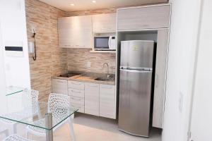 a kitchen with a stainless steel refrigerator and a table at Landscape Comfort Residences in Fortaleza