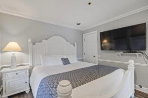 a white bedroom with a large bed and a flat screen tv at 215 Water Street Inn in Boyne City