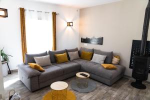 a living room with a gray couch and yellow pillows at La Maison de Jade & Spa in La Roche-de-Glun