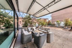 an outdoor patio with wicker furniture and windows at Abacus Hotel in Sesto San Giovanni
