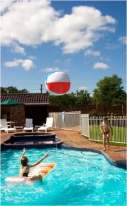 a woman playing with a beach ball in a swimming pool at Acacia Motor Lodge in Coonabarabran