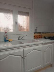 a white kitchen with two sinks and two windows at Villa avec piscine privée in Potinville