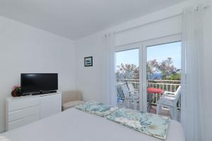 a bedroom with a bed and a television and a balcony at Apartment Zamalin SeaView in Tribunj