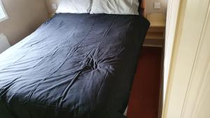 Bett mit blauer Decke in einem Zimmer in der Unterkunft 361 seawick in Saint Osyth