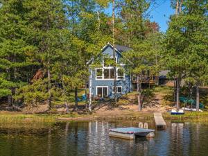 a house sitting on the shore of a body of water at Driftwood Cabin near Eagle River, WI in Saint Germain
