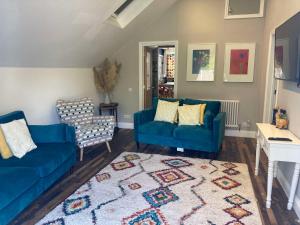 a living room with two blue couches and a rug at Lime Tree Cottage in Tillingham