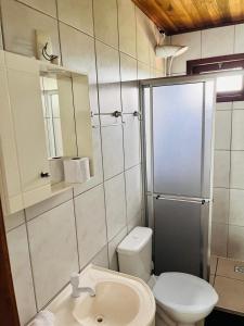 a bathroom with a toilet and a sink and a mirror at SunHouse Praia do Rosa in Praia do Rosa