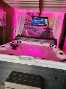 Un dormitorio con bañera de hidromasaje con iluminación rosa. en Love room xoxo, en Norrois