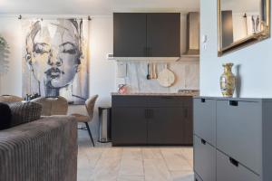 a kitchen with black cabinets and a painting of a woman at De Schelp 58 in Zandvoort