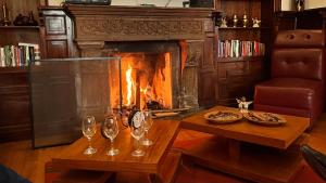 a living room with a fireplace and a table with wine glasses at Hotel Boutique Villa de Sant Refugio de Relajacion in Quito
