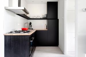 een keuken met zwarte kasten en een fornuis bij Sea Shell apartment in Zandvoort
