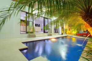 a swimming pool with a palm tree in a house at Kedis Bali Villa in Kuta