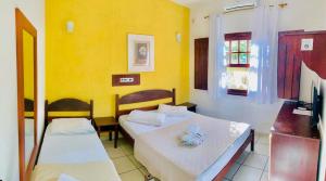 two beds in a room with yellow walls at Brazish Pousada in Paraty