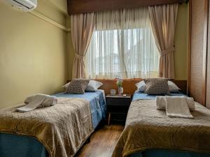 zwei Betten in einem Zimmer mit Fenster in der Unterkunft VV Suítes - Apto Rua Coberta in Gramado