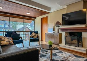 ein Wohnzimmer mit Kamin und Fernseher in der Unterkunft VV Suítes - Apto Rua Coberta in Gramado
