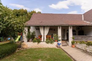 Une petite maison blanche avec des fleurs dans la cour dans l'établissement Marika Vendégháza, à Tokaj