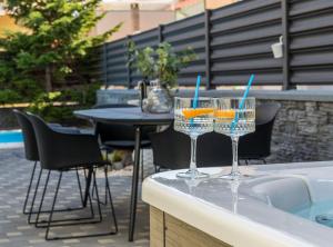 two wine glasses sitting on a counter next to a pool at Villa S in Vodice