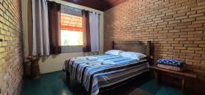 a bedroom with a bed and a brick wall at Refúgio Mantiqueira - Parte Alta Parque Nacional Itatiaia in Itamonte