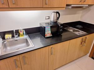 a kitchen counter with a sink and a microwave at Best staycation at Shell residences in MOA complex in Manila