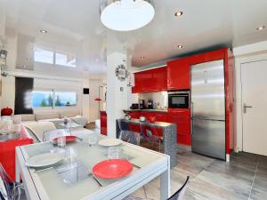 a kitchen and living room with red cabinets and a table at Triplex moderne avec terrasse à Courchevel 1850, près des pistes et services, 3 suites, parking - FR-1-575-145 in Courchevel