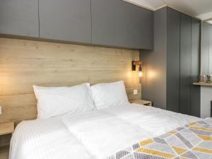 a bedroom with a white bed with a wooden headboard at Hazel in Denny