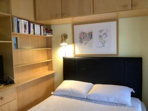 a bedroom with a bed with a black headboard and book shelves at Kitnet Canela Plaza Serrana in Canela
