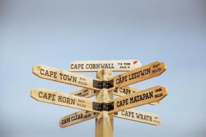 a street sign with distances to different cities at Cape Cornwall Club in St. Just +9 photos