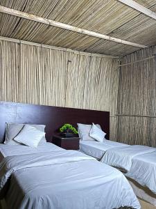 een kamer met 2 bedden en een houten plafond bij Wahiba Bedouin Rustic Camp in Muntarib