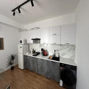 a kitchen with white cabinets and a black dishwasher at Superb loft Tashkent downtown in Tashkent