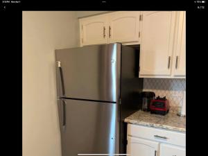 a stainless steel refrigerator in a kitchen with white cabinets at Apt 2 The Mod Squad in Masury