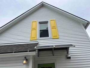 a house with yellow shutters and a window at Apt A The Yellow Shuttered House in Sharon