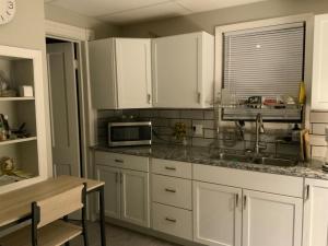 a kitchen with white cabinets and a sink and a microwave at Apt A The Yellow Shuttered House in Sharon