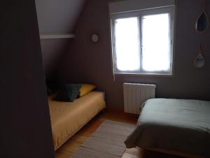 een kleine kamer met twee bedden en een raam bij Cottage du Becquet in Épaignes