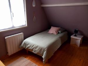 een kleine slaapkamer met een bed met een roze kussen bij Cottage du Becquet in Épaignes