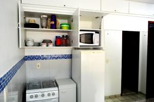 a small kitchen with a stove and a microwave at Costeira Praia 103 in Natal