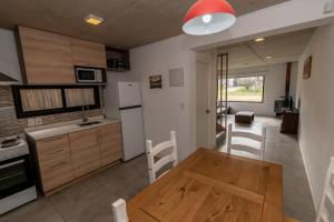 a kitchen and living room with a wooden table and chairs at BAHIA SAN FRANCISCO, casa Albatros a 80 metros del mar, Uruguay in Piriápolis