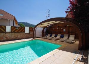 a swimming pool with an arch over it with lounge chairs at Logis Hôtel Les Autanes & Spa in Ancelle