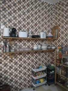a kitchen with a tiled wall with shelves with dishes at Chambre d'hótes Teranga in Thiès +8 photos