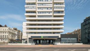 a tall building with a parking lot in front of it at Holiday Inn Brighton Seafront by IHG in Brighton & Hove