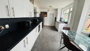 Una cocina con gabinetes blancos y una encimera negra. en Ella street Double room, en Hull
