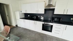 a kitchen with white cabinets and a black counter top at Ella street Double room in Hull