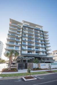 a large apartment building with palm trees in front of it at Verve on Cotton Tree in Maroochydore